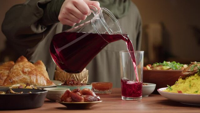 Pouring juice, Muslim family dinner, Ramadan, iftar. Couscous with chicken, fried eggplant, samsa and dolma, mediterranean cuisine. Religious holiday, holy month. Traditional Eastern Halal food.