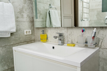 Modern bathroom interior with metal faucet and ceramic white sink.
