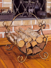 Firewood stack in a bronze basket standing by the fireplace