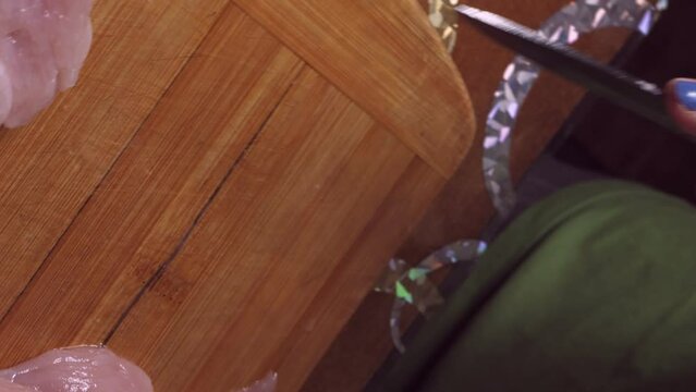 Women's hands cut a turkey fillet on a wooden board with a knife. Medium plan