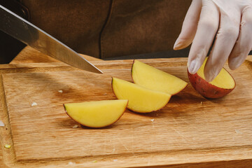 Slicing potatoes on a wooden chopping board. Cooking food. Sliced potatoes. Shallow depth of field