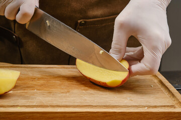 Slicing potatoes on a wooden chopping board. Cooking food. Sliced potatoes. Shallow depth of field