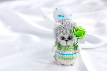 a knitted kitten with knitting needles, colored balls of thread in a basket. Creative workshop on needlework handmade