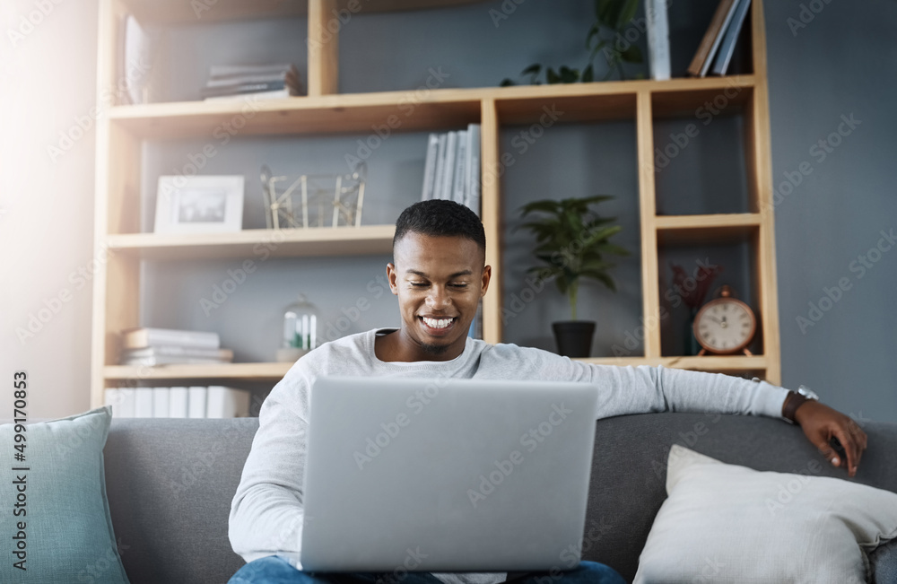 Poster everything is all good this side. shot of a handsome young man using his laptop while sitting on a s