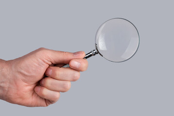 Man hand holding magnifying glass. Data search and analysis, conducting research, nuances, important details study, preparation for exams concept. High quality photo