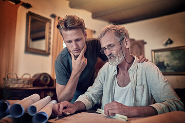 Putting their thinking caps on. Shot of a father and his son working on a design for their family business at home.