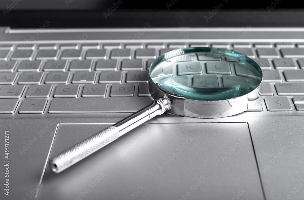 Poster magnifying glass on laptop keyboard. internet surfing concept. online databases study. audit conduct