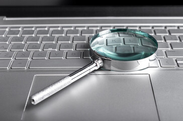 Magnifying glass on laptop keyboard. Internet surfing concept. Online databases study. Audit conducting using computer. High quality photo