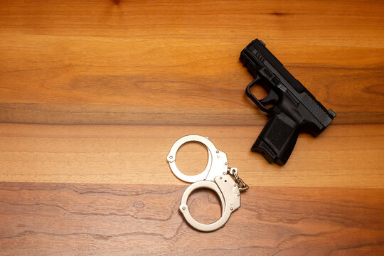 Gun and Handcuffs on Wooden Table