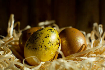 Ugotowane złoto żółte jajka wielkanocne na sianie w tle deski.