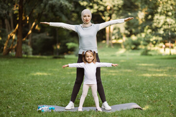 Family sport fitness activity. Pretty Muslim woman in sportswear and hijab and her preschool cute...
