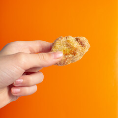 Holding a fried snack chicken nuggets on an orange background in your hand