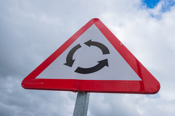 roundabout sign with cloudy sky in the background