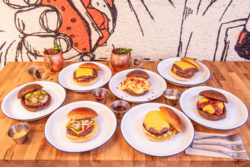 A pile of beef burgers with melted cheddar cheese, jalapeños, lettuce and fried bacon, brioche bread, sauces and drinks