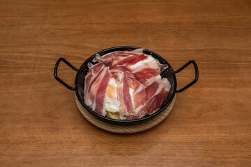 broken egg recipe This dish is one of the most celebrated in Spanish cuisine. They are delicious and simple, a gastronomic wonder with potatoes and serrano ham in a black enamel container.