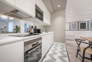 Fototapeta na wymiar kitchen with white stone countertops, white cabinets, stainless steel appliances and integrated extractor hood