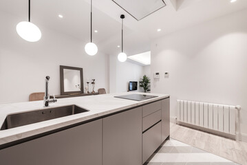 kitchen island with white stone countertops, gray cabinets, stainless steel appliances, spherical lampshades and sideboard with mirror