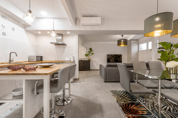 The kitchen with wood countertops with white gloss wood cabinets, matching island and tall gray leather chairs with chrome legs, glass dining table and matching upholstered sofa
