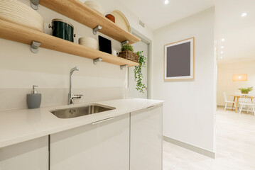 Kitchen with white stone countertops, white wood cabinets with light wood shelves above, and dining table with chairs in the background