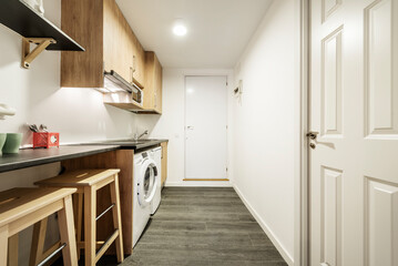 Kitchen with dark gray wooden countertops, wooden furniture, wooden stools under the countertop and white appliances