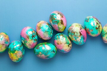 Minimalistic Easter composition. Golden paint eggs on blue background. Greeting trendy color concept. Top view, flat lay.