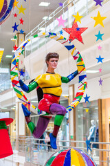 Mannequin - a rainbow-colored acrobat on a hoop with colorful decorations at a carnival or amusement park
