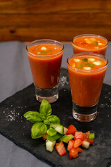 Small glasses of shot or liqueur with Andalusian Gazpacho. A cold vegetable and organic soup or drink that is drunk in summer or hot days. Vertical orientation.