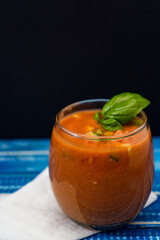 Important Glass with the refreshing Andalusian Gazpacho on a blue wooden table. Cold vegetable and organic soup or drink that is drunk in summer or hot days. Copy Space.