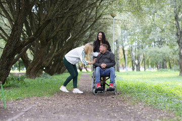 Happy young disabled man communicates with girlfriends in park