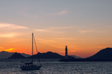 Fototapeta na wymiar Beautiful view of sunset at Lighthouse in marina with yachts in Turgutreis, Bodrum, Turkey.