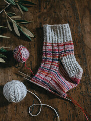Hand knitted sock with needles and grey yarn ball on dark wooden background. Concept for handmade...