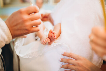 Baptism ceremony of a baby. Close up of tiny baby feet, the sacrament of baptism. The godfather holds the child in his arms. small legs of a newborn baby