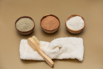 Organic green, red, white face mask clay in wooden bowls with soft sponge bandage and bamboo and goat hair brush on beige background. Home skin care concept.Self care