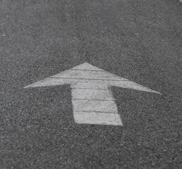 black and white photo of white arrow painted on pavement representing straight ahead or going...