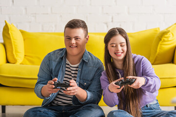 KYIV, UKRAINE - JANUARY 21, 2022: Positive teenagers with down syndrome playing video game at home.