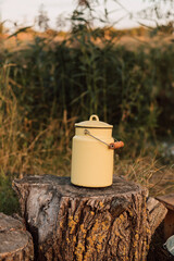 Yellow metal milk container stands on a stump in the village