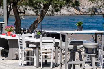 A beautiful outdoor bar decorated with flowers and ashtrays with an amazing view of the famous beach of Perissa in Santorini