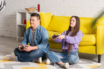 KYIV, UKRAINE - JANUARY 21, 2022: Teenagers with down syndrome playing video game at home.