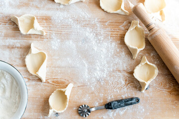 Cropped view of the roller pin and raw bakery from dough laying at the wooden table