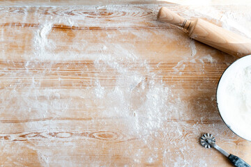 Top view of the rolling pin, plate and flour on the wooden table