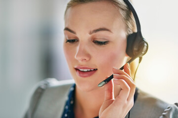 Please hold while I connect your call. Shot of an attractive young woman wearing a headset in the office.