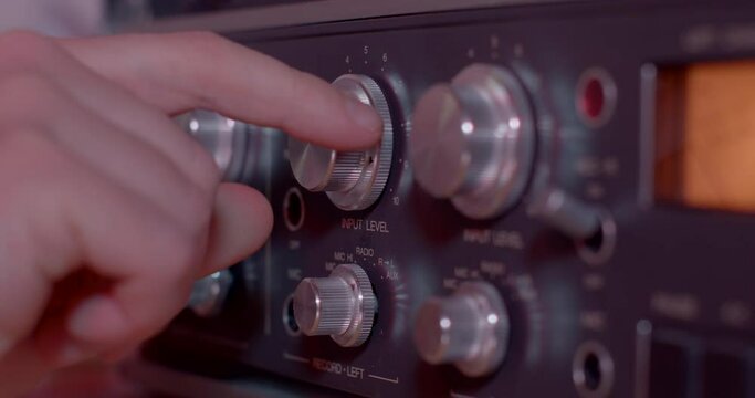 Close-up finger twists sound recording frequencies control spy specialist sets up listening device. Sound level.