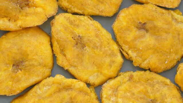 Fried platanos on plate. Sliced and cooked tostones. Rotating