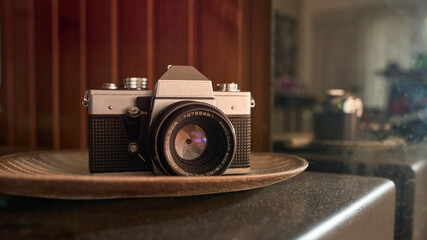 Vintage camera on a brown table and behind a reflection of it