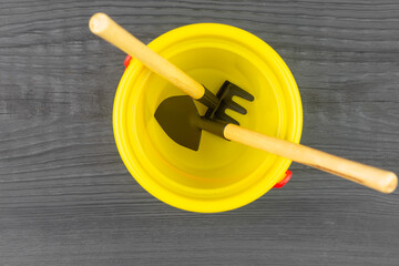 Garden working tool (shovel and rake) in a plastic bucket.
