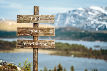 find your destination text quote written on wooden signpost outdoors in nature with lake and mountain scenery in the background. Moody feeling.