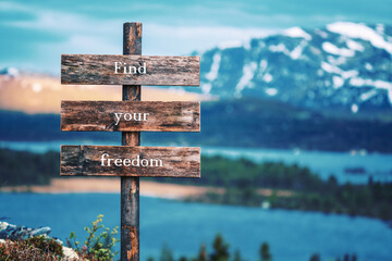 find your freedom text quote written on wooden signpost outdoors in nature with lake and mountain...