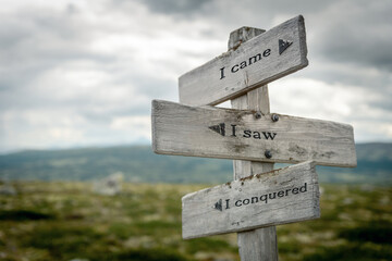 i came i saw i conquered text quote written in wooden signpost outdoors in nature. Moody theme feeling.