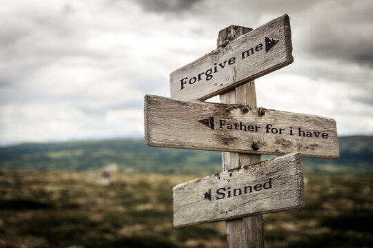 forgive me father for i have sinned text quote written in wooden signpost outdoors in nature. Moody theme feeling.