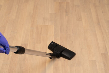Hand holding vacuum cleaner brush on  parquet boards background. Copy space.